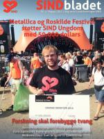 Ung mand med SIND t-shirt foran orange scene på Roskilde med donationskort i hænderne