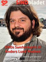 Anders Lund Madsen i profil smiler med vand og by i baggrunden